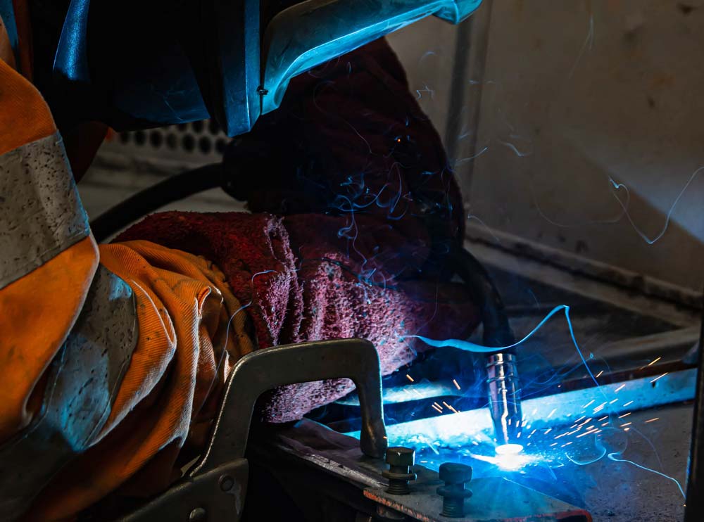 An individual engaged in welding, with vibrant sparks flying from the metal surface