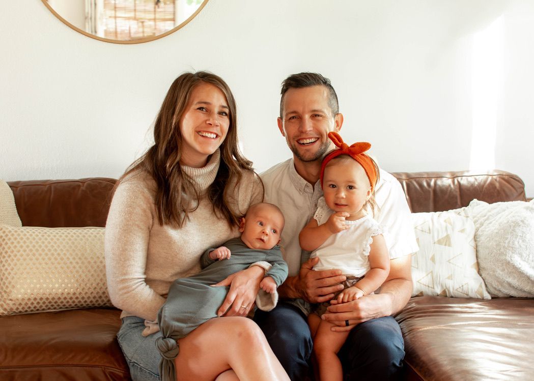 A family is posing for a picture while sitting on a couch.