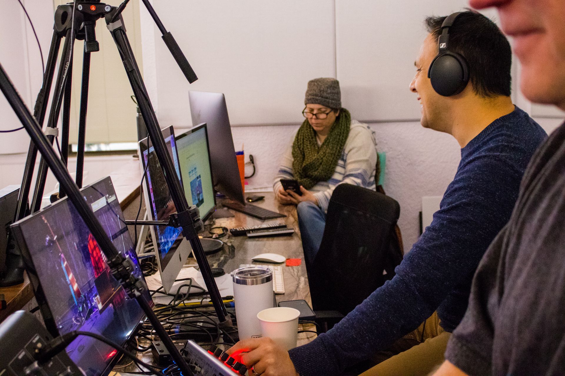 A man wearing headphones is sitting at a desk in front of a computer.