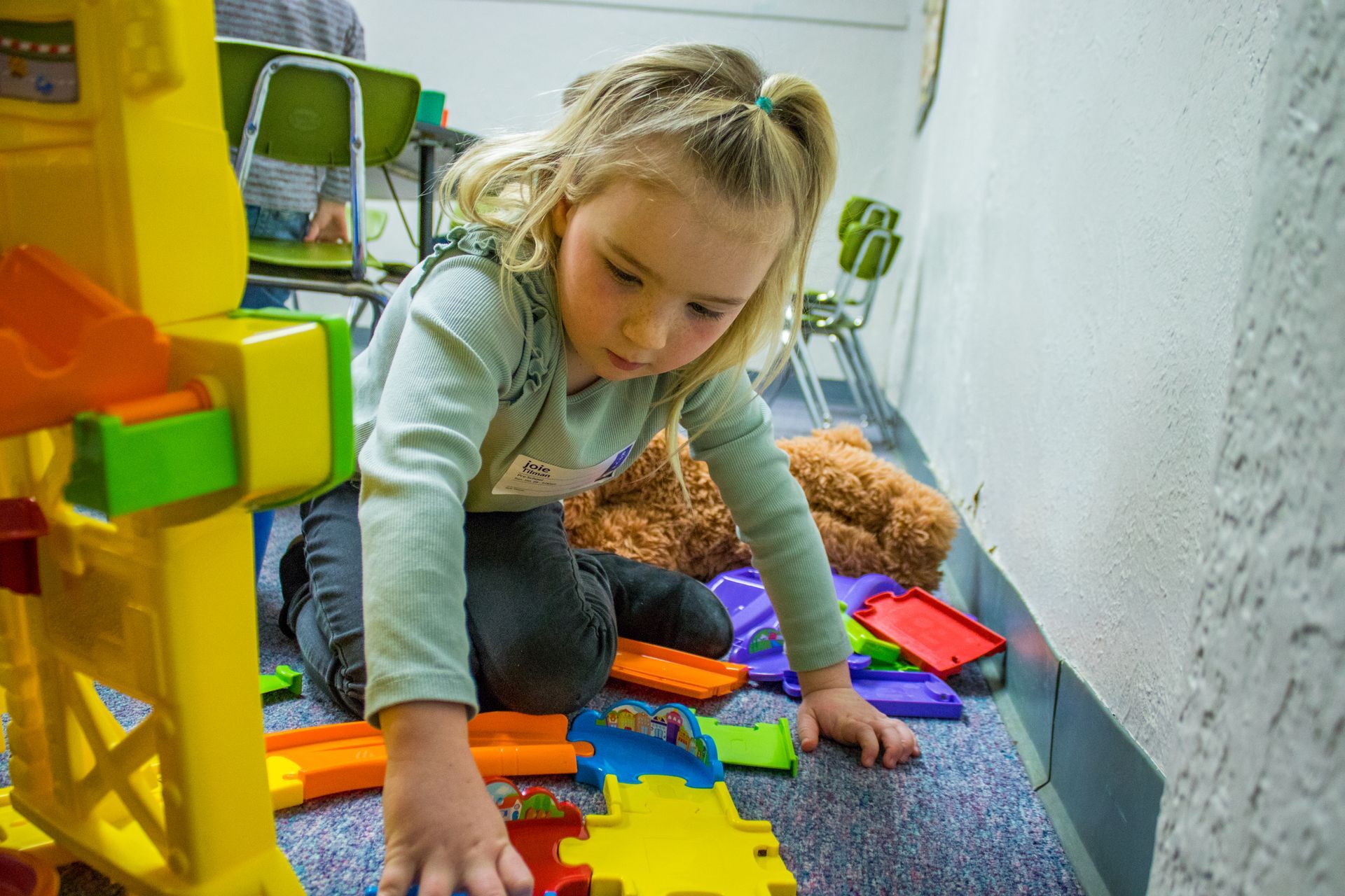 A little girl is playing with toys on the floor.