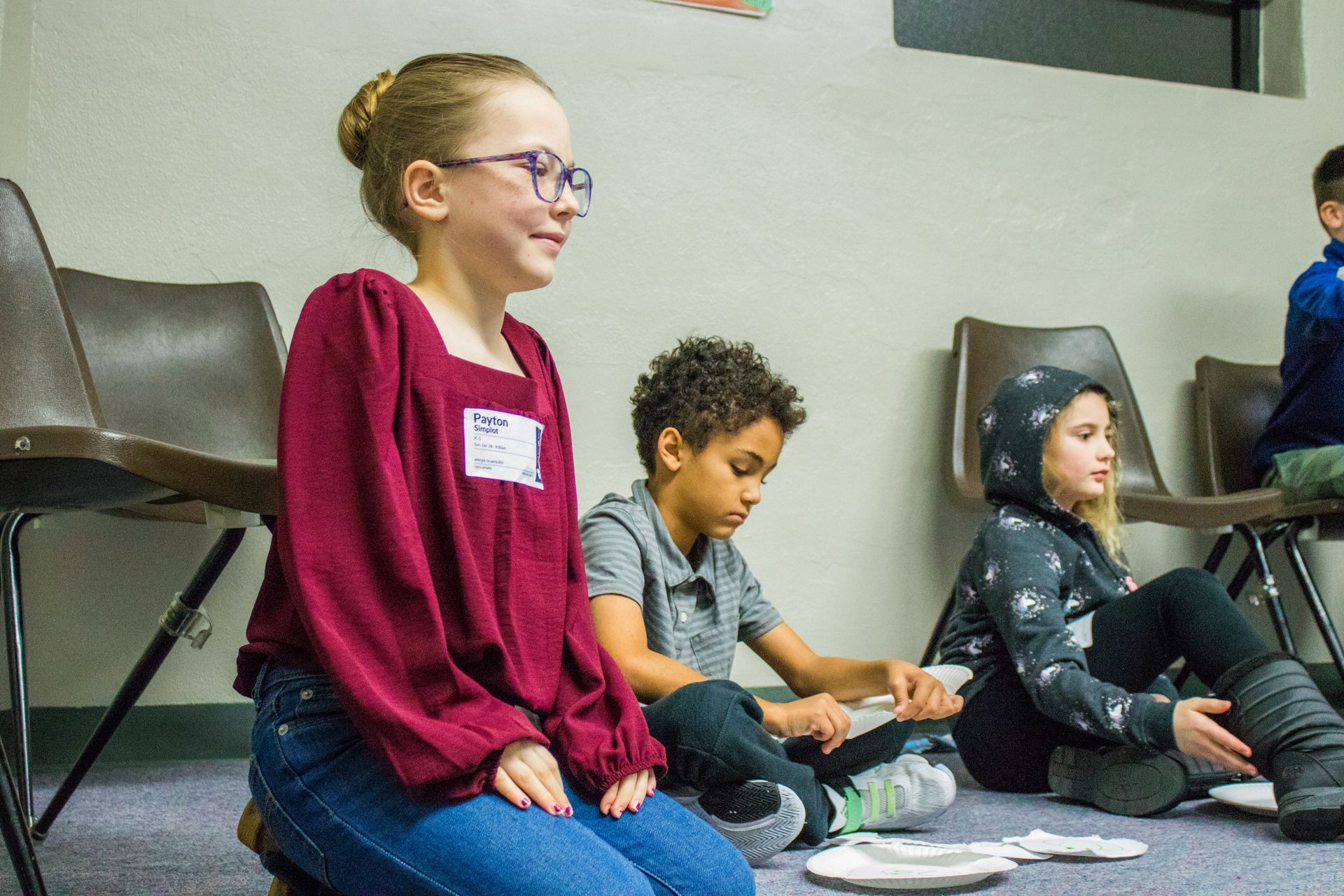 A group of children are sitting on the floor in a room.