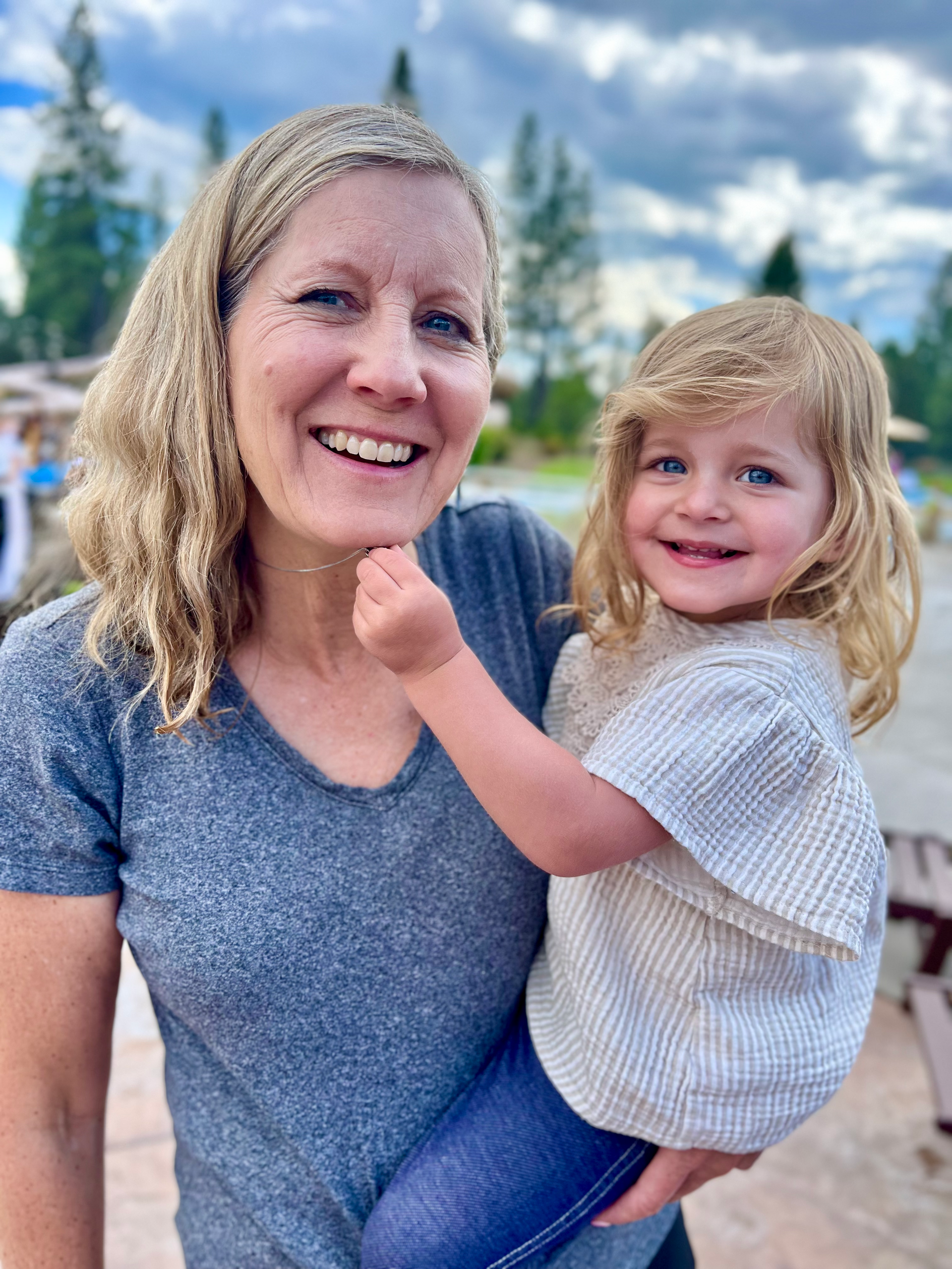 A woman is holding a little girl in her arms and smiling.