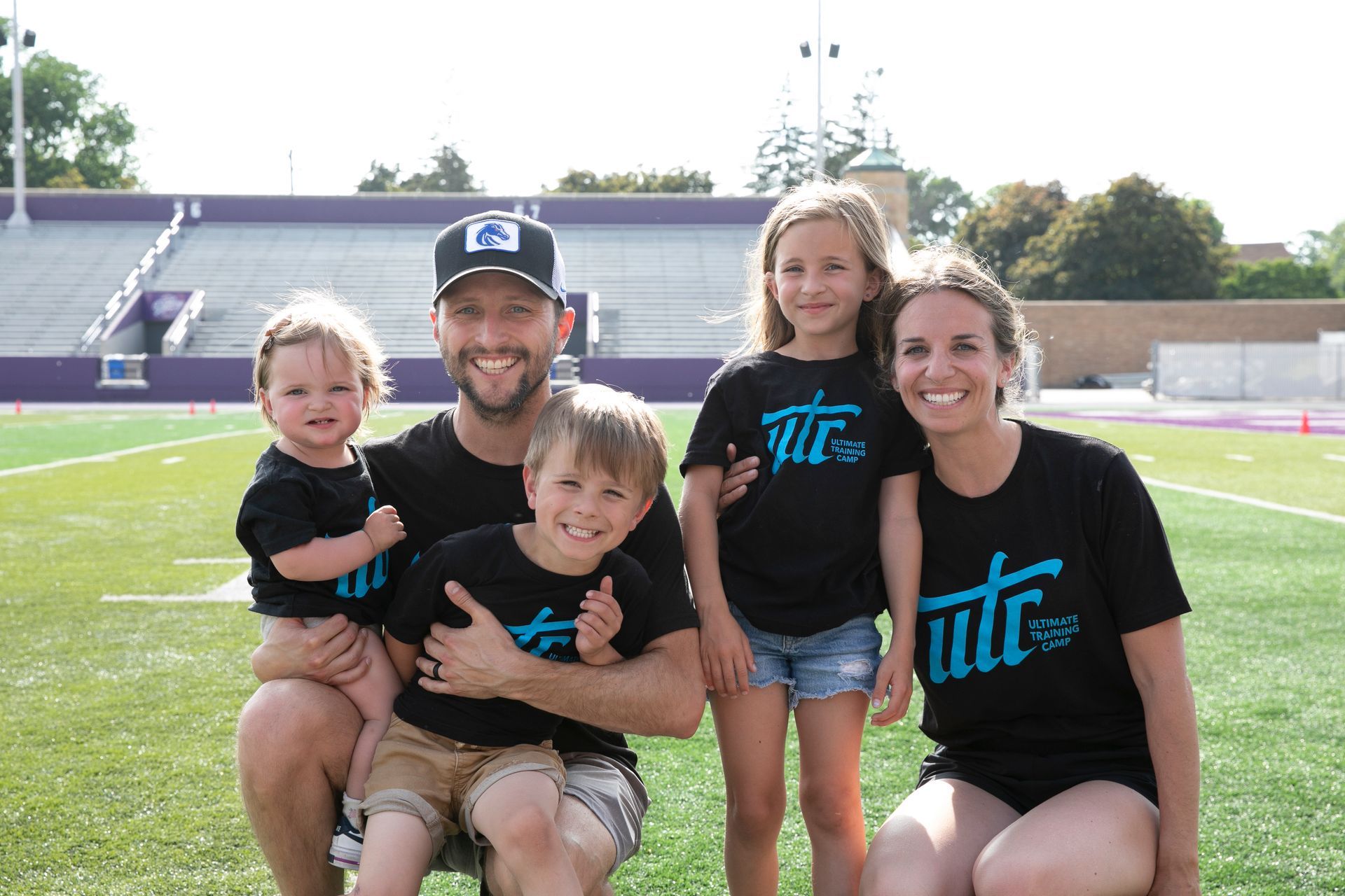 A family is posing for a picture on a football field.