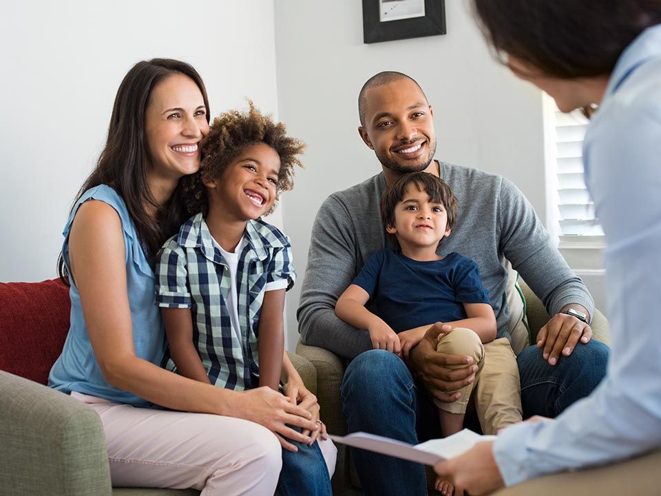 A family is sitting on a couch talking to a counselor.