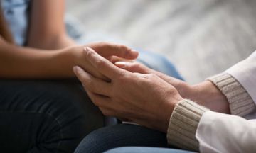 A close up of a person holding another person 's hand.