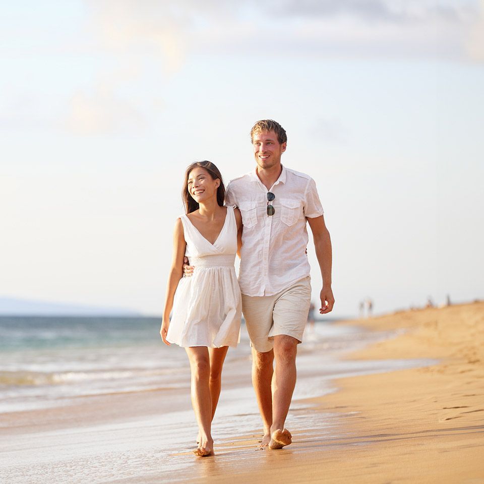 A man and a woman are walking on the beach