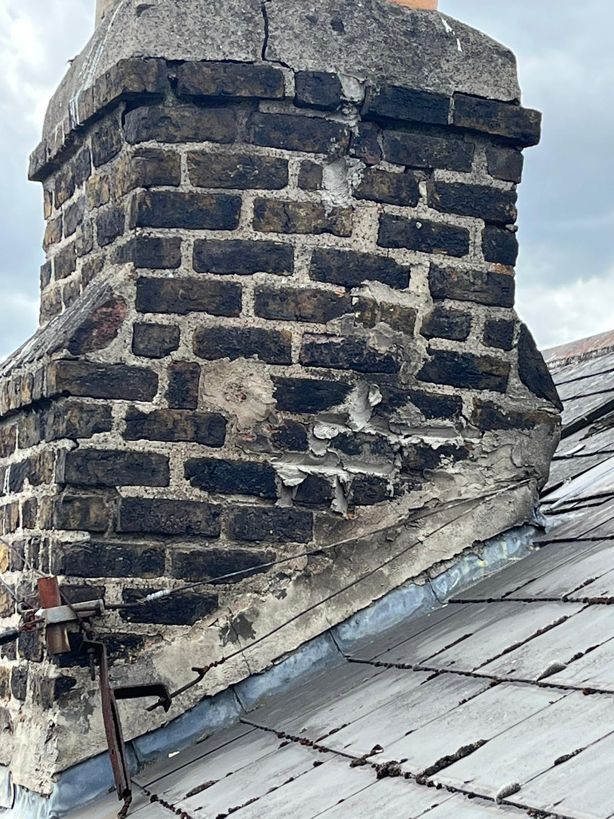 A brick chimney is sitting on top of a roof.