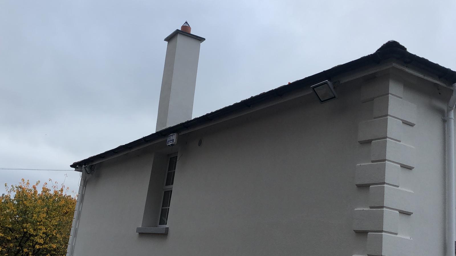 A white house with a chimney on the side of it.