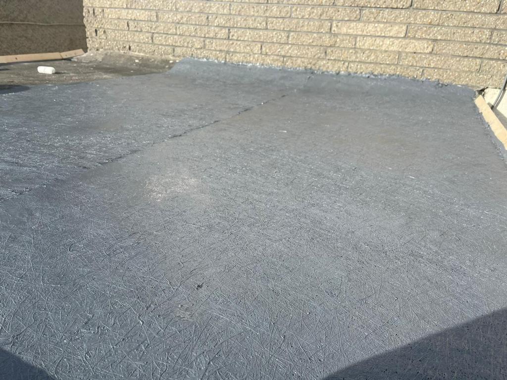 A gray asphalt driveway with a brick wall in the background.