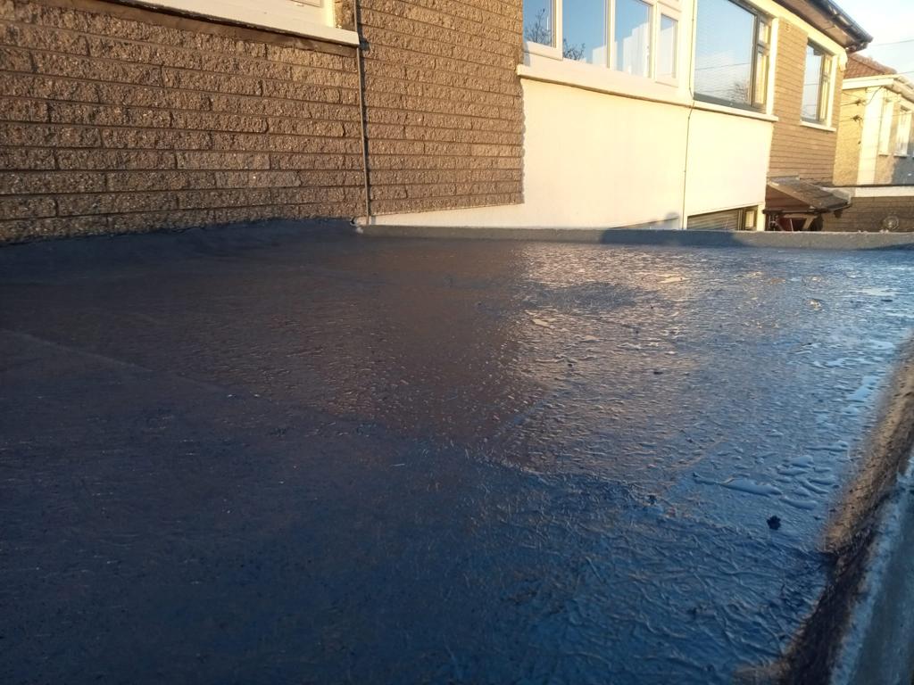A black roof with a brick wall in the background.