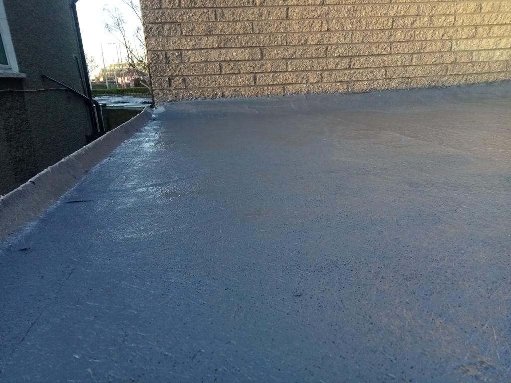 A brick wall with a concrete floor in front of it.