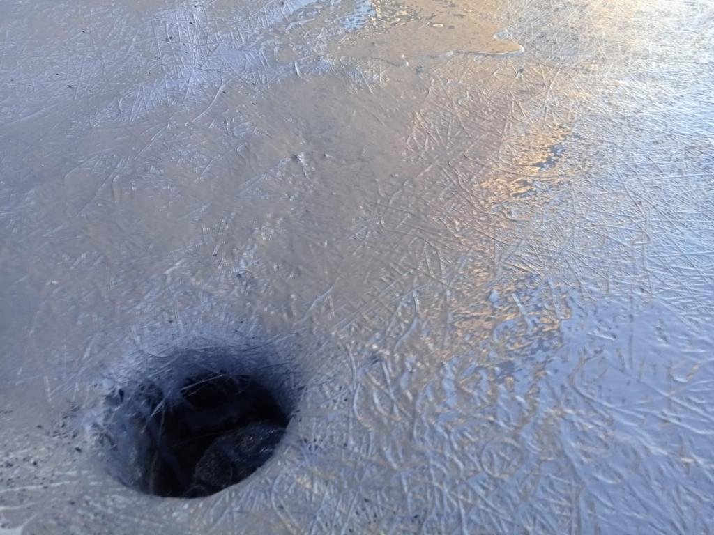 There is a hole in the ice that looks like a hole in the ground.