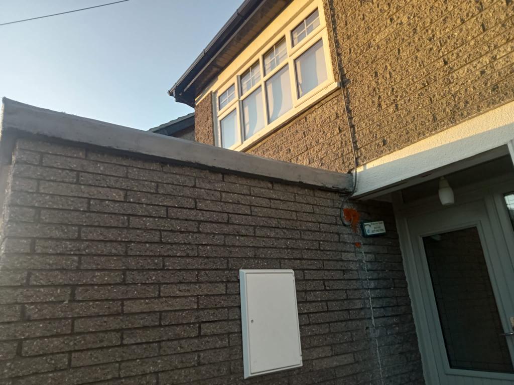 A brick wall with a white box on it next to a door.