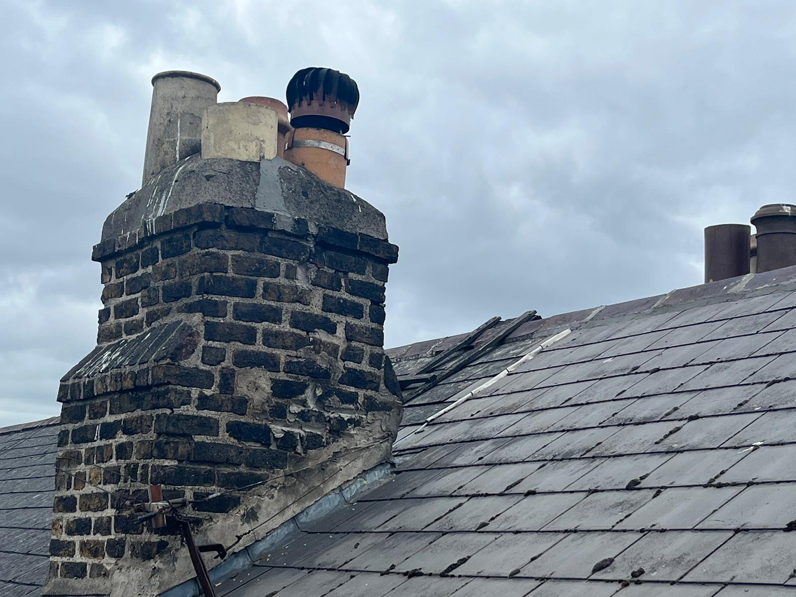 A chimney on top of a roof with a cloudy sky in the background