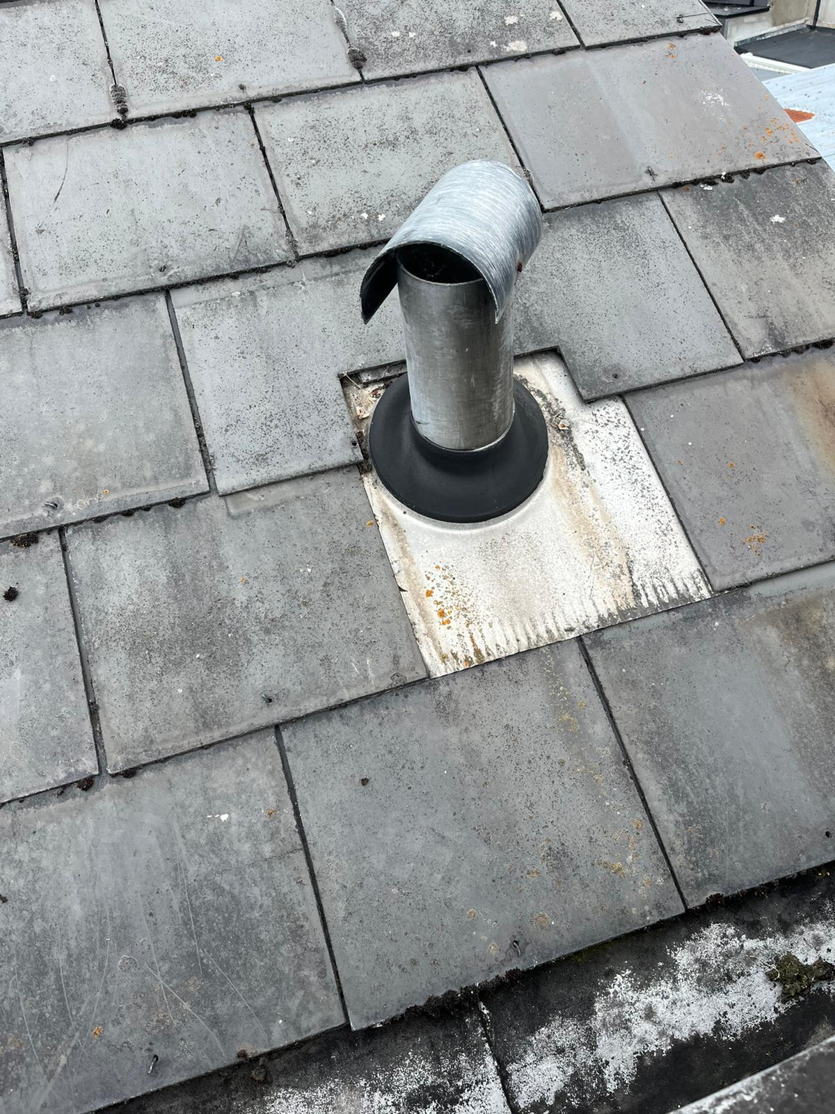 A metal pipe is sitting on top of a tiled roof.
