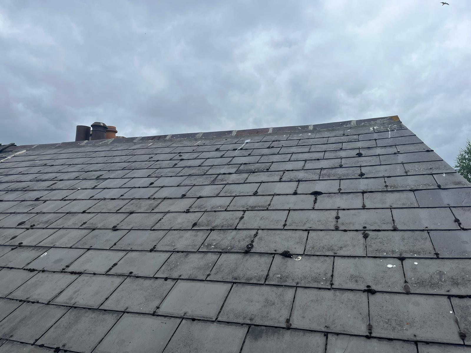 A roof with a chimney on it and a cloudy sky in the background.