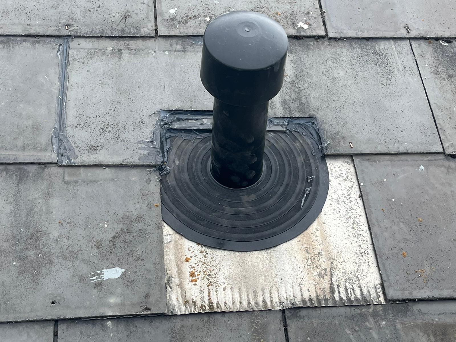 A black pipe is sitting on a tiled roof