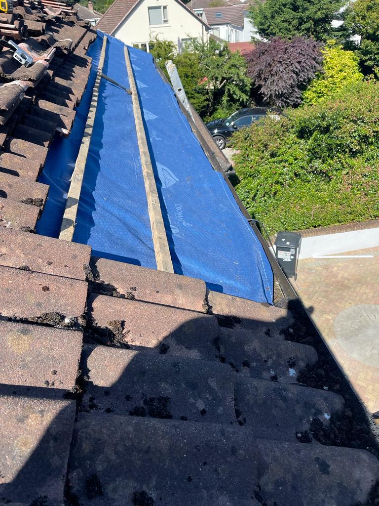 A blue tarp is covering the roof of a house.