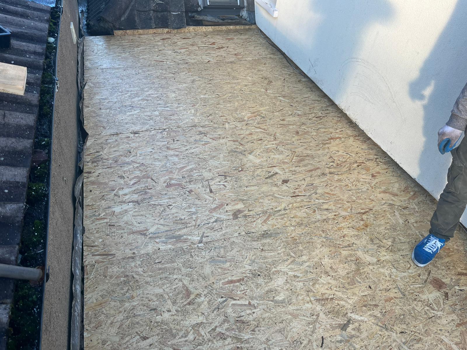 A person is standing on a wooden floor next to a wall.