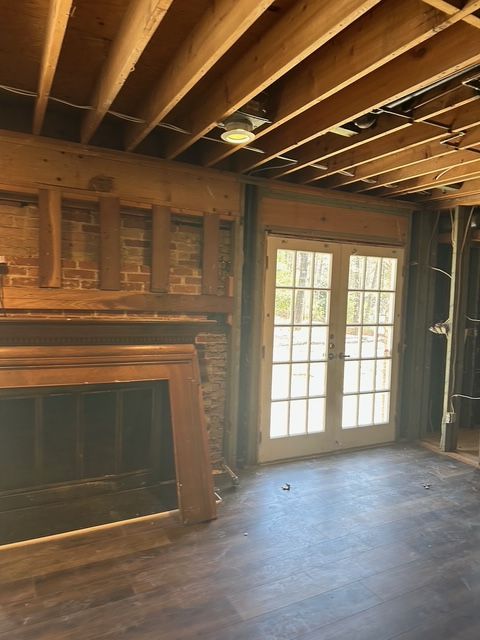 A room under construction with a fireplace, exposed wood beams, and a dark floor.