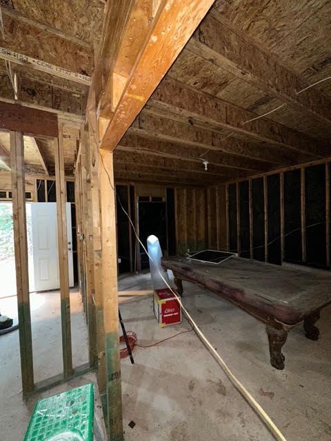 Interior of a room under construction with exposed wooden framing and a pool table. Interior of a room under construction with exposed wooden framing and a pool table.