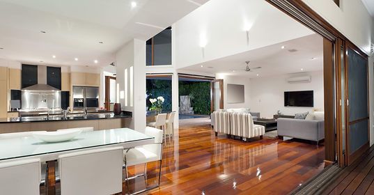 Open-plan modern home interior with a kitchen, dining area, and living room leading to an outdoor deck.