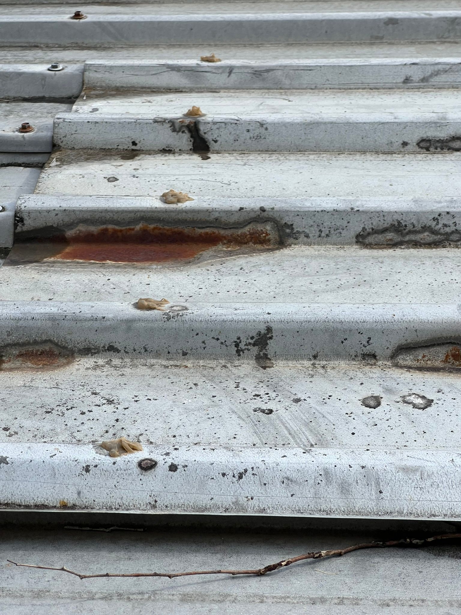 Corroded corrugated metal roofing with significant rust damage was identified during a building inspection.
