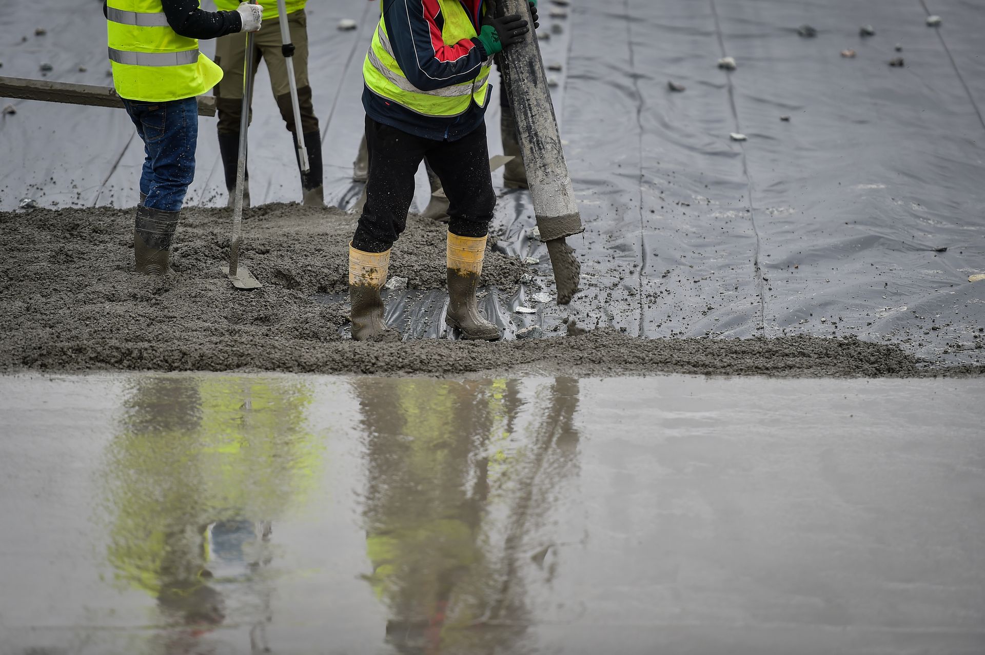A group of construction workers are working on a concrete floor.