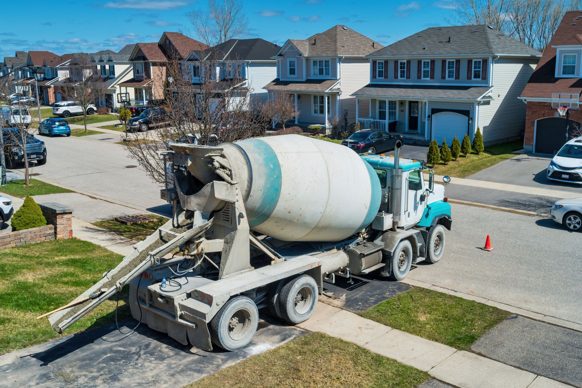 A concrete mixer truck is driving down a residential street.