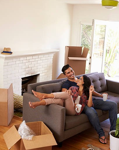 couple sitting on couch, laughing, in new home