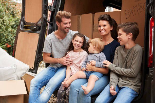 family sitting in back of vehicle with boxes in it