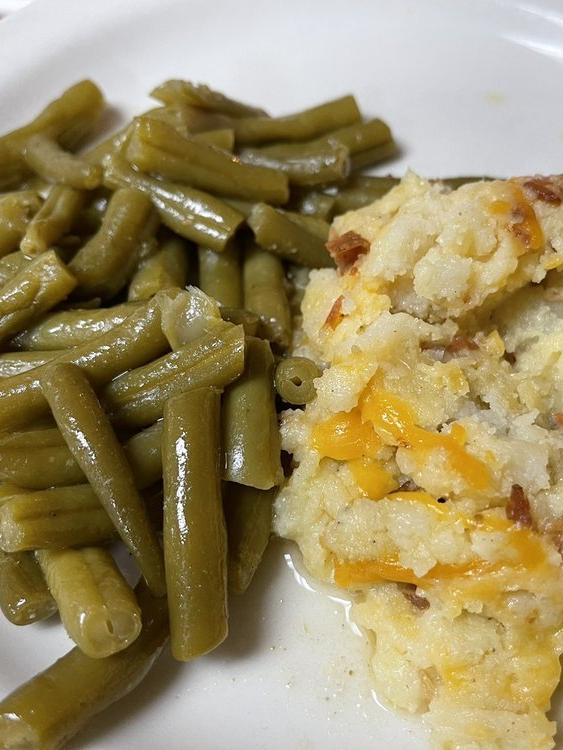 A white plate topped with green beans and mashed potatoes.