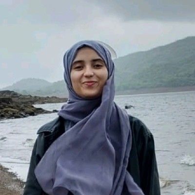 A woman in a hijab is standing next to a body of water.