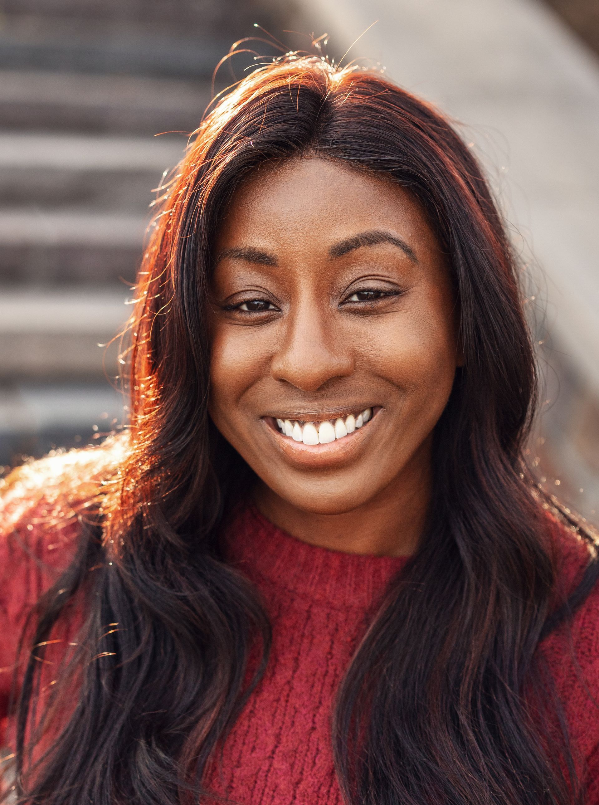 A close up of a woman wearing a red sweater and smiling.