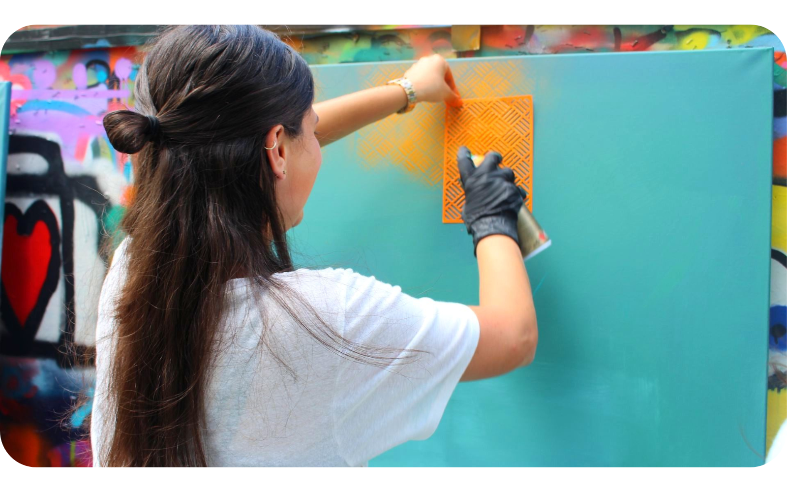 Meisje die bezig is met graffiti spuiten tijdens een grafitti workshop