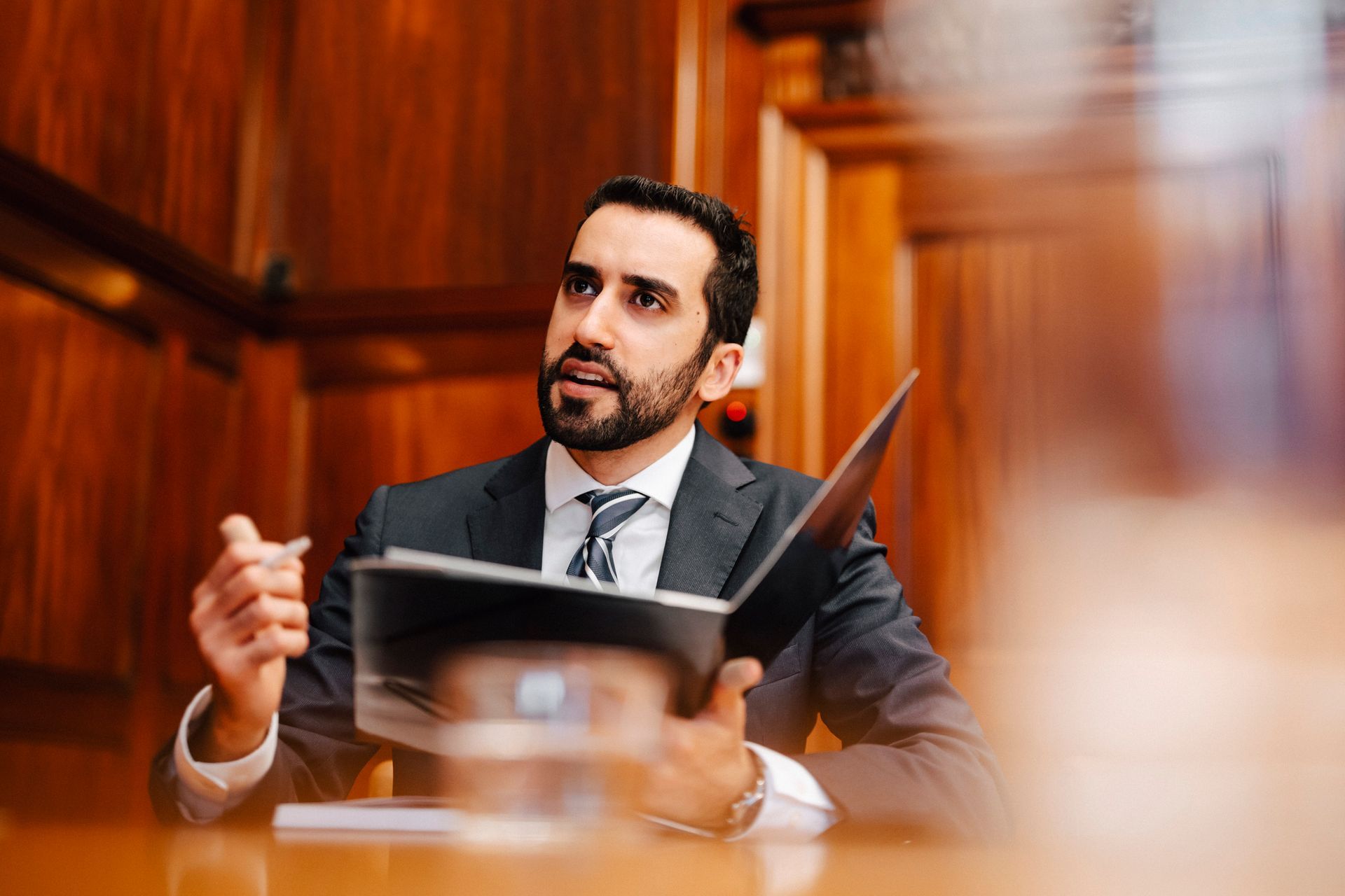 A man in a suit and tie is sitting at a table reading a book