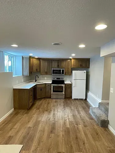 Kitchen with wood cabinets, white countertops, stainless steel appliances, and wood-look flooring.