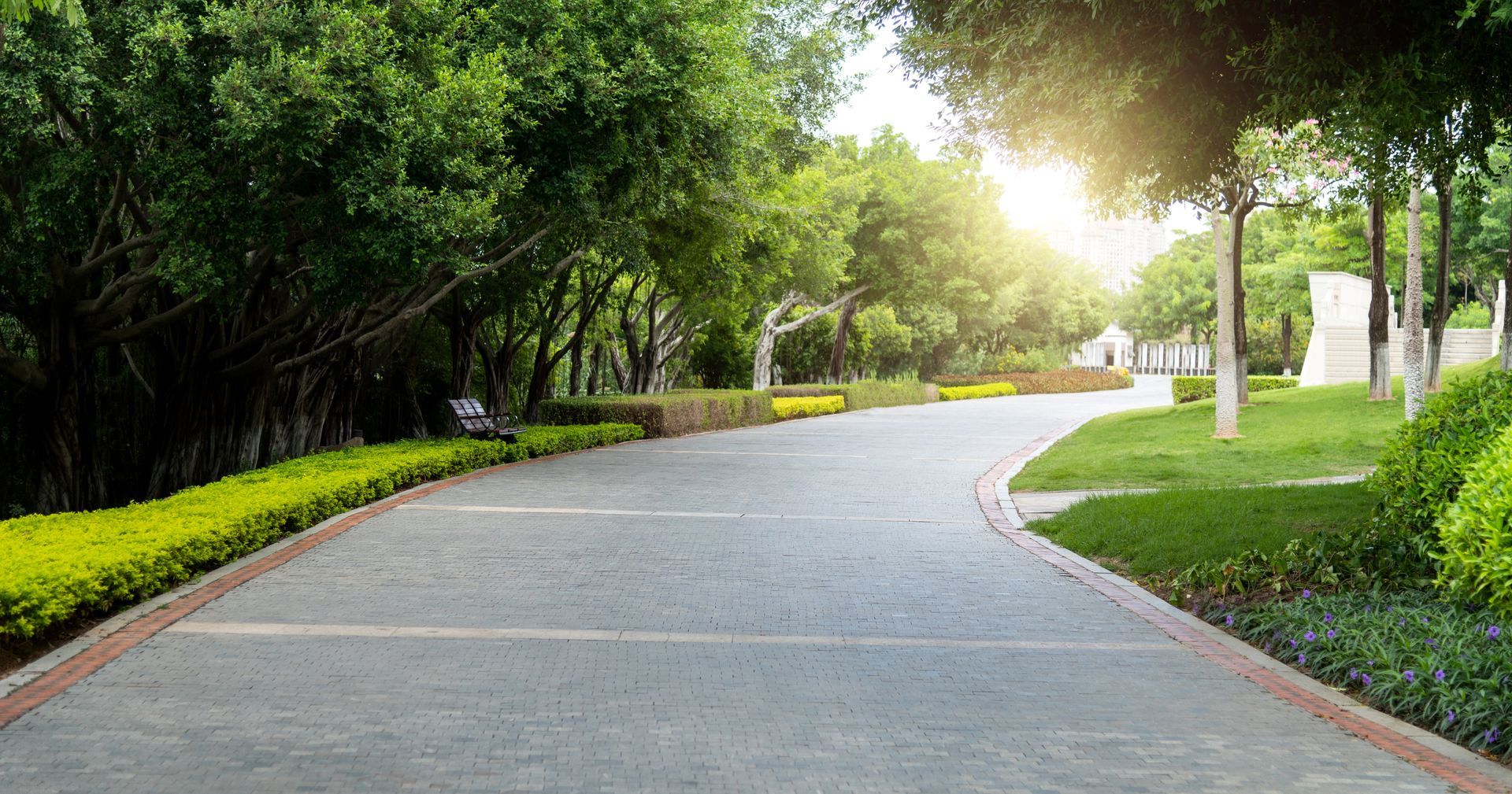 Woman in straw hat smiles, holding wine glass near a lake.
