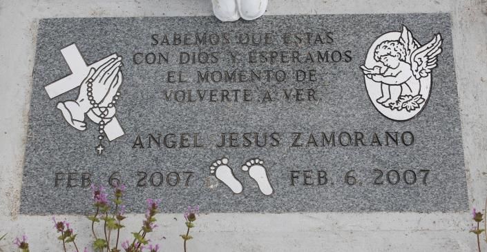 Gray memorial plaque with Spanish inscription, crosses, angel, and dates February 6, 2007.