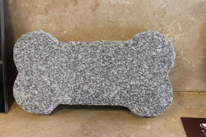 Gray speckled bone-shaped stone object on a beige tiled floor