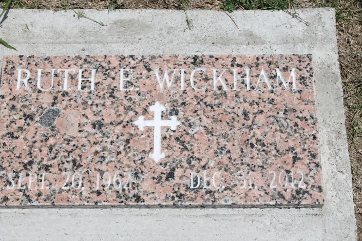 Gravestone for Ruth E. Wickham with a white cross on pink granite plaque.