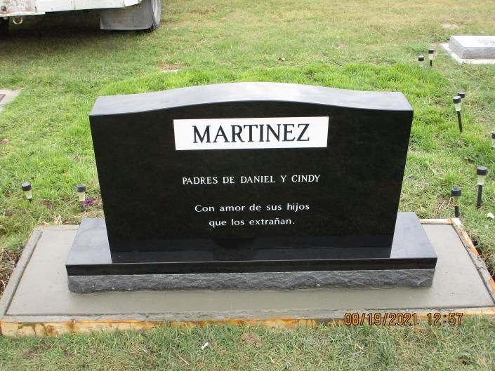 Black granite Martinez family gravestone with Spanish inscription on a grassy cemetery plot