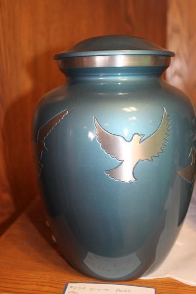 Blue urn with a silver dove design on a wooden shelf