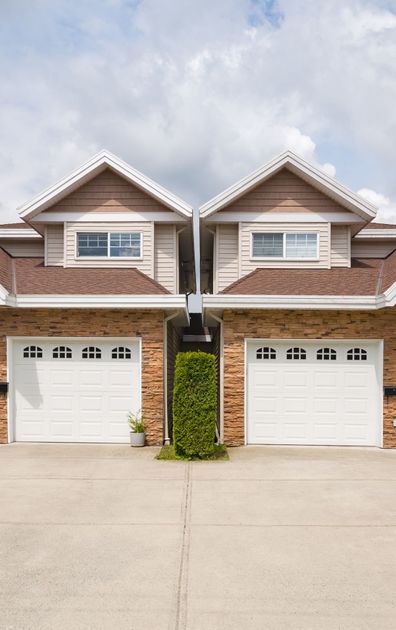 Two Identical Houses with White Garage Doors Are Next to Each Other.