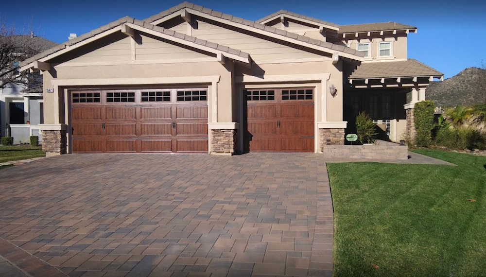 A Large House with Two Garage Doors and A Brick Driveway
