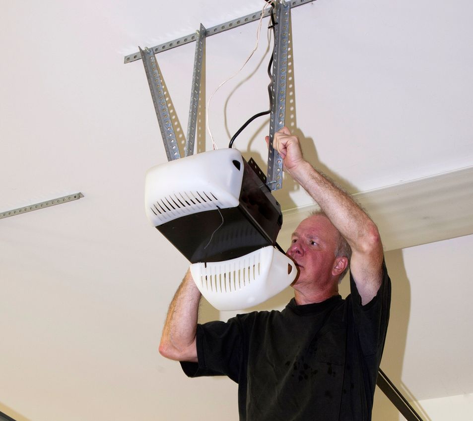 A Man Is Fixing a Garage Door Opener in A Garage