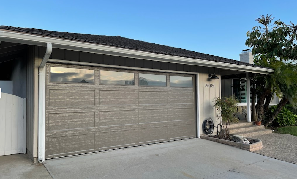A House with A Large Garage Door and A White Fence
