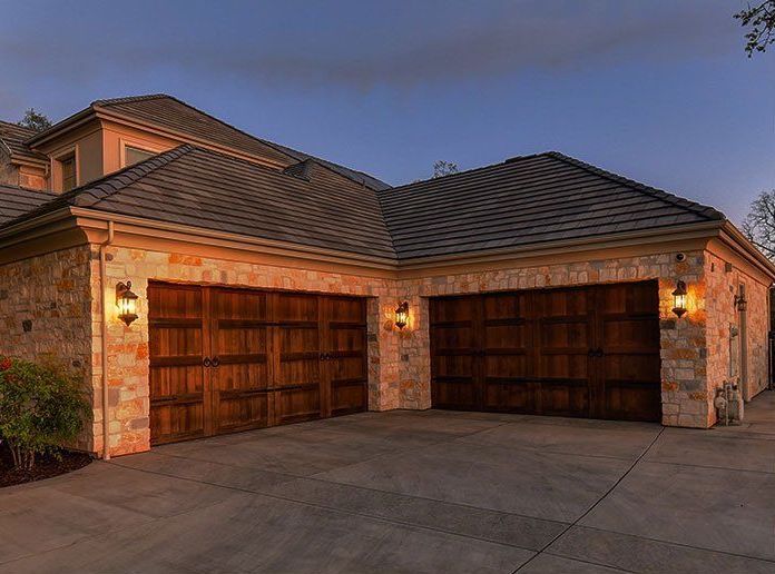 A Large Brick House with Two Wooden Garage Doors.