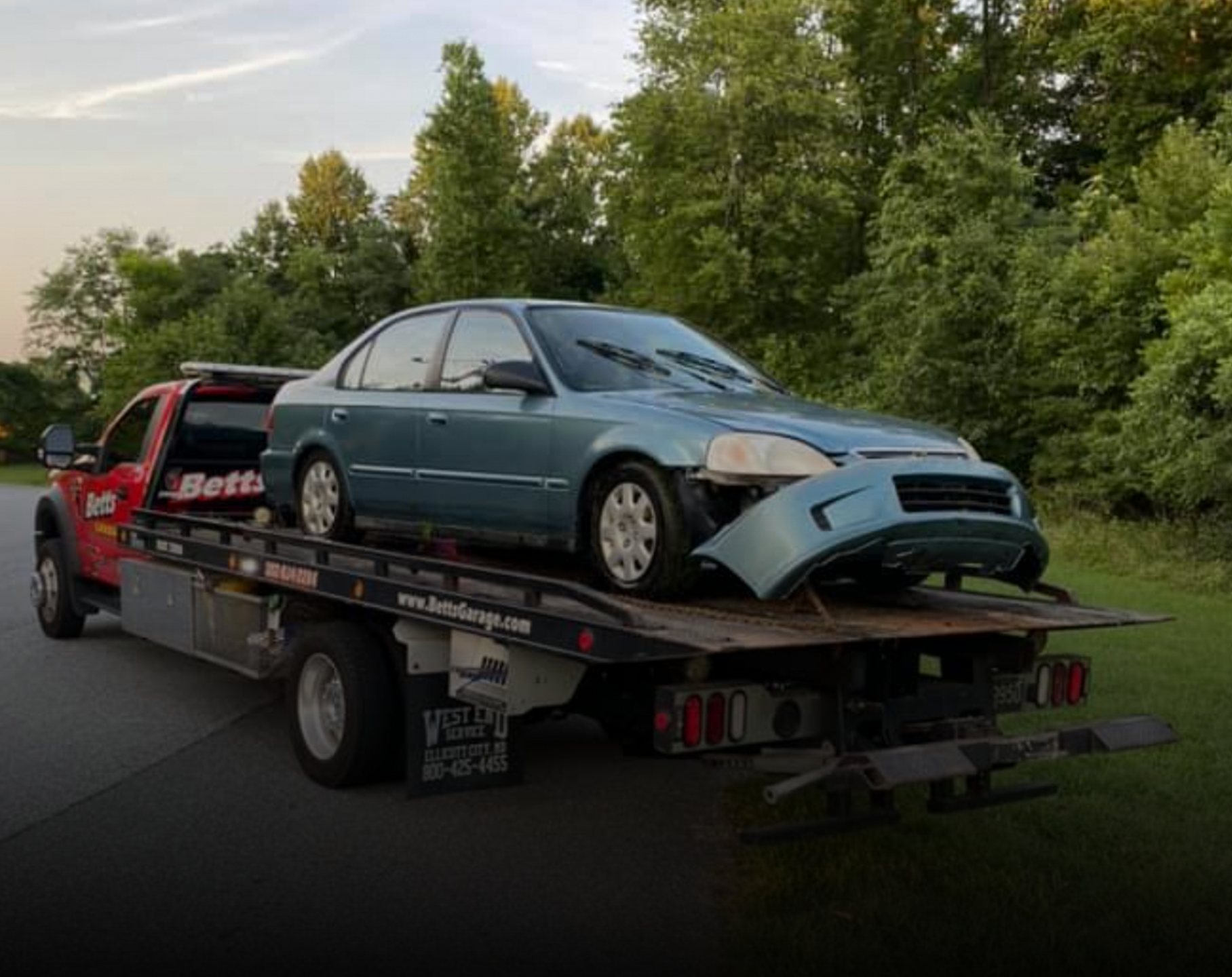 Betts Garage tow truck transporting damaged car after collision