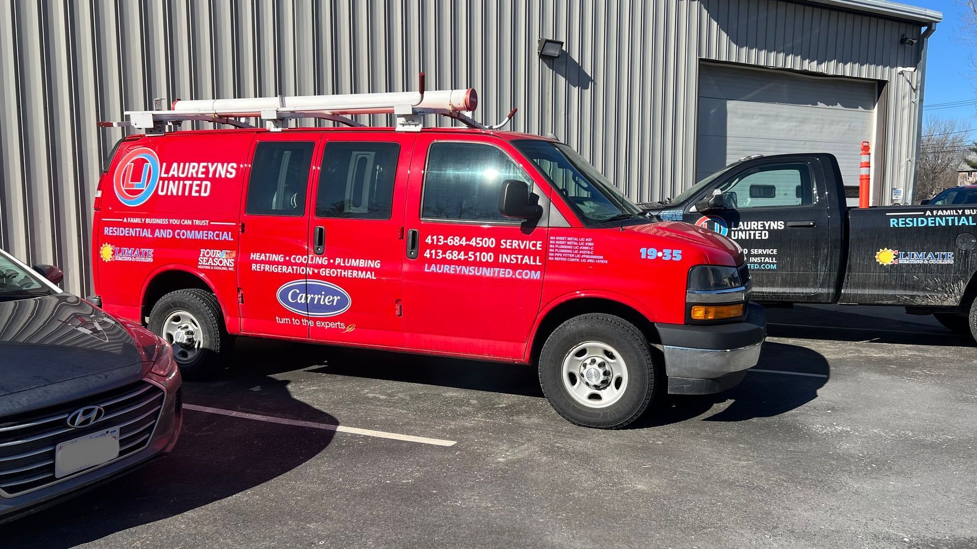 A red van is parked in a parking lot next to a black truck.